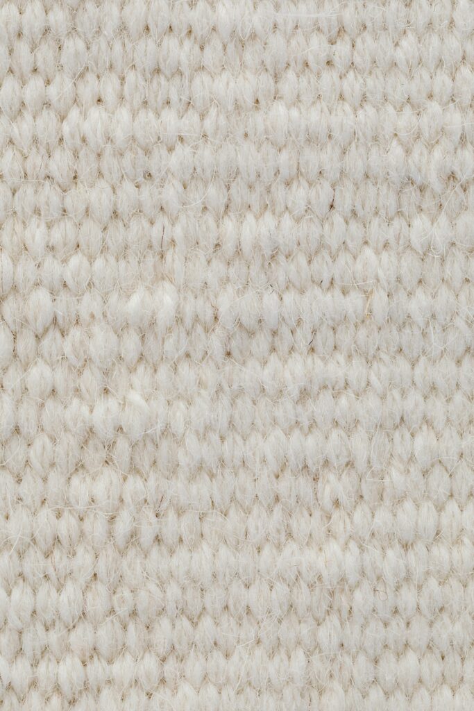 Detailed view of a beige wool textile fabric, showcasing its texture and softness.