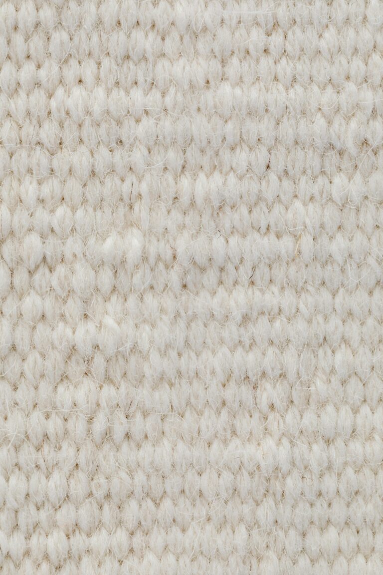 Detailed view of a beige wool textile fabric, showcasing its texture and softness.